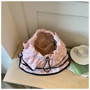 Détail de sac seau plissé rose, sac bandoulière décontracté en tissu avec cordon.