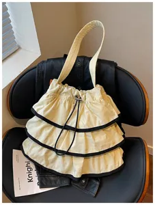 Vue détaillée du sac seau à bandoulière blanc cassé à volants avec bordure noire.