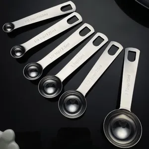 Cucharas medidoras de acero inoxidable en primer plano para repostería y café en polvo.