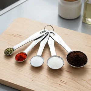 Detailed view of stainless steel measuring spoons set with engraved capacity marks on wood.