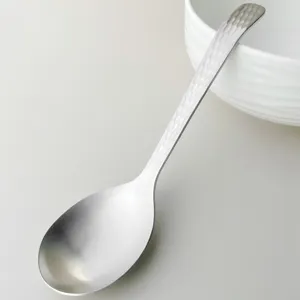 Stainless steel soup spoon close-up, hammered handle design, detail view for kitchenware.