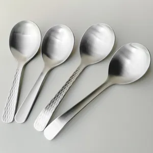 Stainless steel serving spoon set detail, featuring hammered and smooth handle designs.