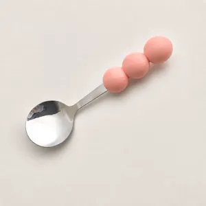 Stainless steel spoon featuring cute macaron pink round balls handle for dessert and cake.