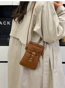 Minimalist brown leather crossbody phone bag with drawstring closure and cute heart metal charm.