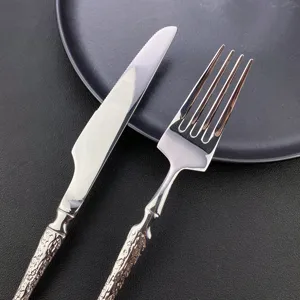 Stainless steel cutlery detail shot showing textured handle steak knife and western dinner fork.