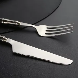 Détail de couverts en acier inoxydable avec fourchette et couteau à manche imitation bambou.