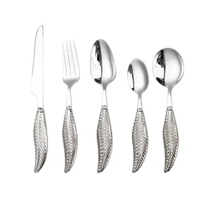 Stainless steel cutlery set with ornate feather handle design close up detail view.