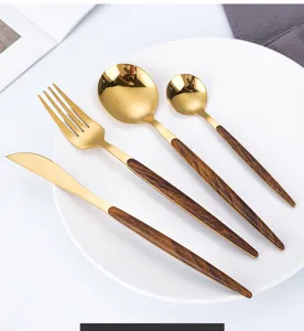 Detail shot of luxury gold cutlery set with wood grain handles, elegant stainless steel tableware.