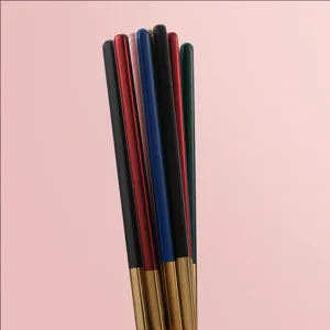Dettagli bacchette in acciaio inossidabile con manici multicolore e punte dorate lucide.