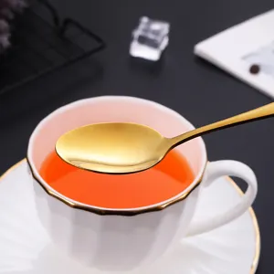 Ensemble de coutellerie élégant avec une cuillère dorée et une tasse en céramique blanche.