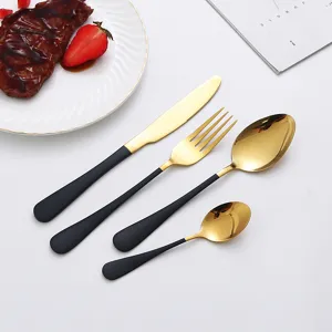 Detailed close-up shot of stainless steel cutlery set with shiny gold finish and matte black handles.