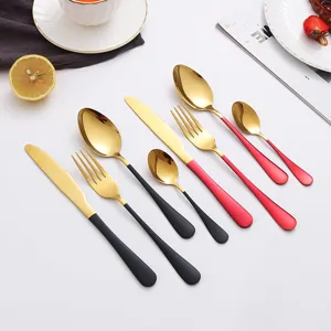 Stainless steel flatware set with gold titanium finish and black red handles for fine dining.