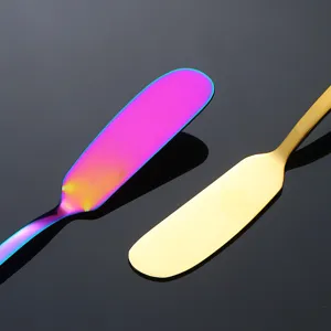 Photo de détail d'un couteau à beurre en acier inoxydable aux finitions colorées et dorées.