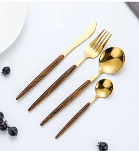 Close-up detail of luxury gold cutlery set with wood grain handle for fine dining aesthetics.