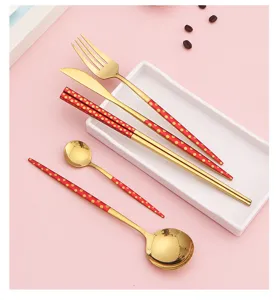 Ensemble de couverts en acier inoxydable avec finition dorée et pois rouges, chic.