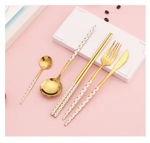 Set de couverts en acier inoxydable doré avec des poignées à pois blancs pour table.