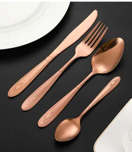 Detailed close-up of rose gold stainless steel cutlery set featuring vintage embossed handle design.
