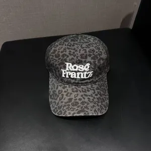 Vista detallada de la gorra de béisbol con estampado de leopardo gris y bordado.