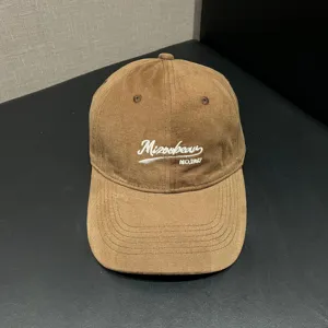 Close-up of the brown corduroy baseball cap with front embroidered lettering and fine stitching.