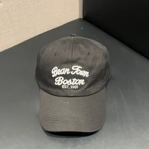 Close-up detail view of the dark grey retro baseball hat featuring stylish white embroidered text.