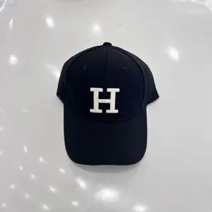 Black baseball hat detail featuring a white embroidered letter H on the front crown.