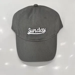 Dettaglio cappellino da baseball grigio con testo Sunday ricamato in bianco e visiera.