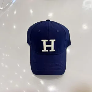 Classic navy blue baseball cap with white embroidered H letter detail, curved brim.