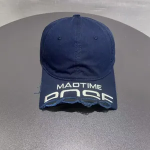 Vista dettagliata di un berretto da baseball blu scuro con ricamo bianco e visiera usurata.