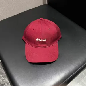 Detailed shot of a maroon baseball cap with white embroidered Black lettering on surface.