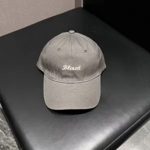 Grey baseball cap detail view featuring front white embroidered letter design texture.