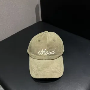 Close-up detail view of cotton corduroy baseball cap with mood embroidery and curved brim.
