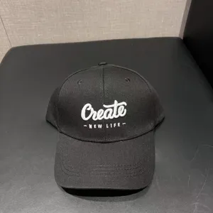Detail shot of a black baseball cap with white embroidered Create text, wide brim casual hat.