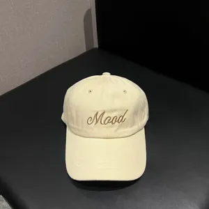 Detailed view of the beige brushed cotton baseball cap featuring embroidered Mood text on front.