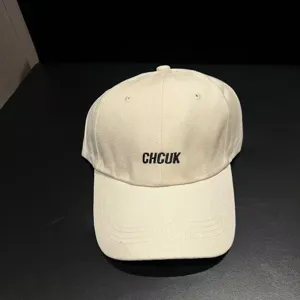 Close-up detail view of the beige brushed cotton baseball cap featuring embroidered lettering.