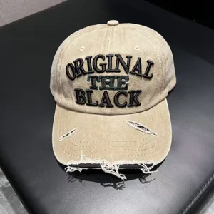 Close-up detail of vintage distressed beige baseball cap with black embroidered text.