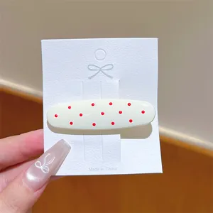 Dettaglio ravvicinato di fermaglio per capelli a pois dolce coreano con design ovale chiaro.