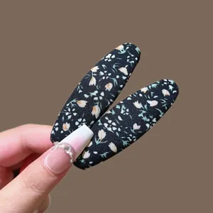Primer plano horquilla tela floral negra, detalle pasador flequillo estilo vintage.