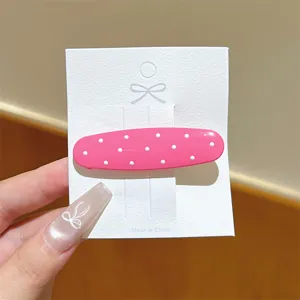 Dolce molletta per capelli rosa a pois con cartoncino bianco, accessorio minimalista.