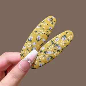 Primer plano de pinzas para el cabello de tela floral vintage, diseño ovalado, dulce.
