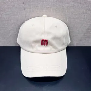 Minimalist off-white baseball cap with red embroidered m letter, casual curved brim sun hat.