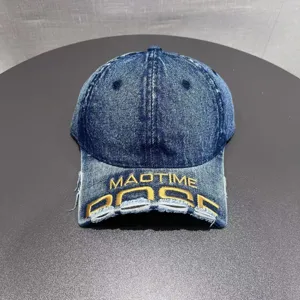 Primo piano del berretto da baseball in denim delavé con ricamo giallo e visiera strappata.