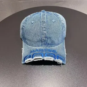 Dettaglio berretto da baseball in denim strappato, ricamo frontale, stile streetwear.