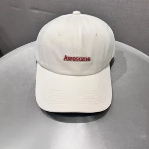White cotton baseball cap close-up featuring red Awesome embroidery detail for daily casual wear.