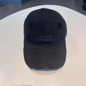 Black distressed baseball cap with front slogan embroidery, casual streetwear detail.