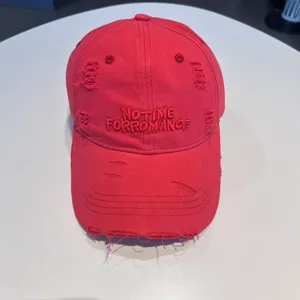 Detailed close-up view of a red distressed baseball cap featuring stylish embroidered design.