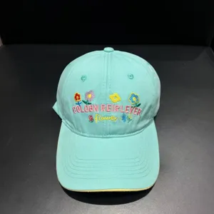 Detailed view of mint green baseball cap with floral and letter embroidery for summer style.