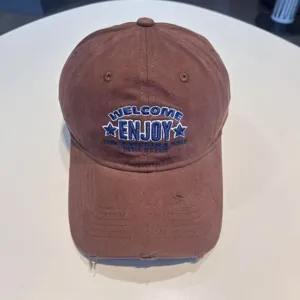 Brown washed cotton baseball cap featuring blue embroidered text and distressed brim.