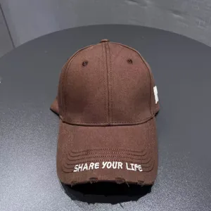 Brown baseball cap with embroidered white letters, stylish washed vintage distressed brim design.