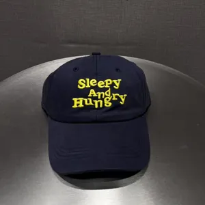 Navy blue baseball cap with yellow letter embroidery, detailed view of front design and fabric.