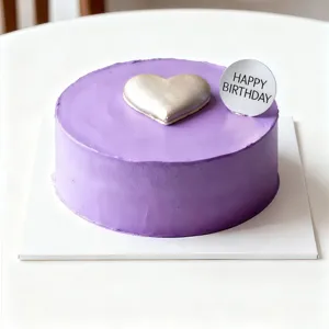 Gros plan détaillé d'un joli gâteau d'anniversaire violet avec topper cœur argenté.